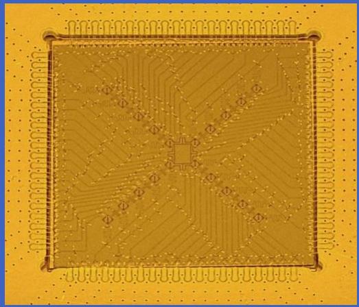 Close-up of a golden printed circuit board with visible traces and pads, mounted on a yellow grid background (no text or